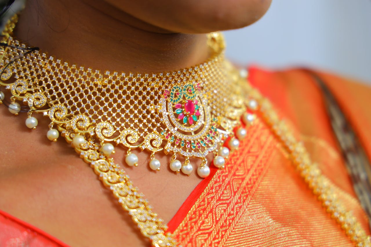 Home Close-up of a gold and pearl choker necklace worn with traditional attire, highlighting intricate details.