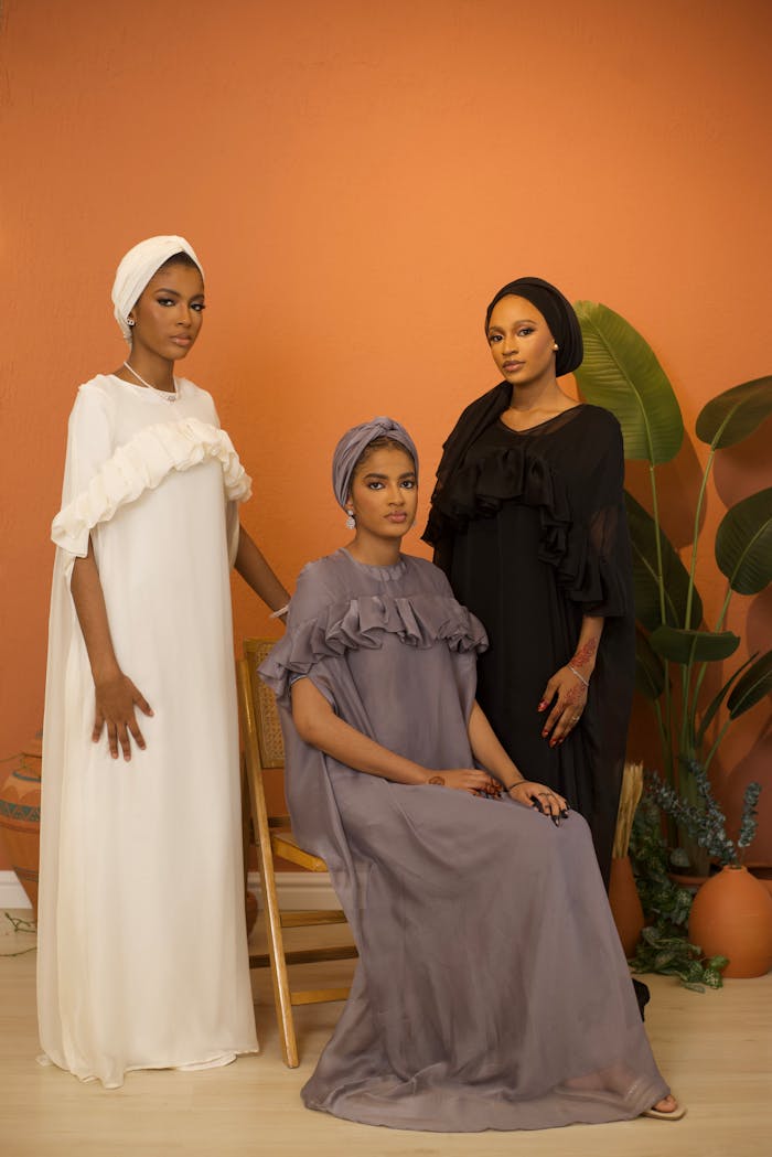 Home Three women in elegant dresses showcasing cultural fashion in a studio setting.