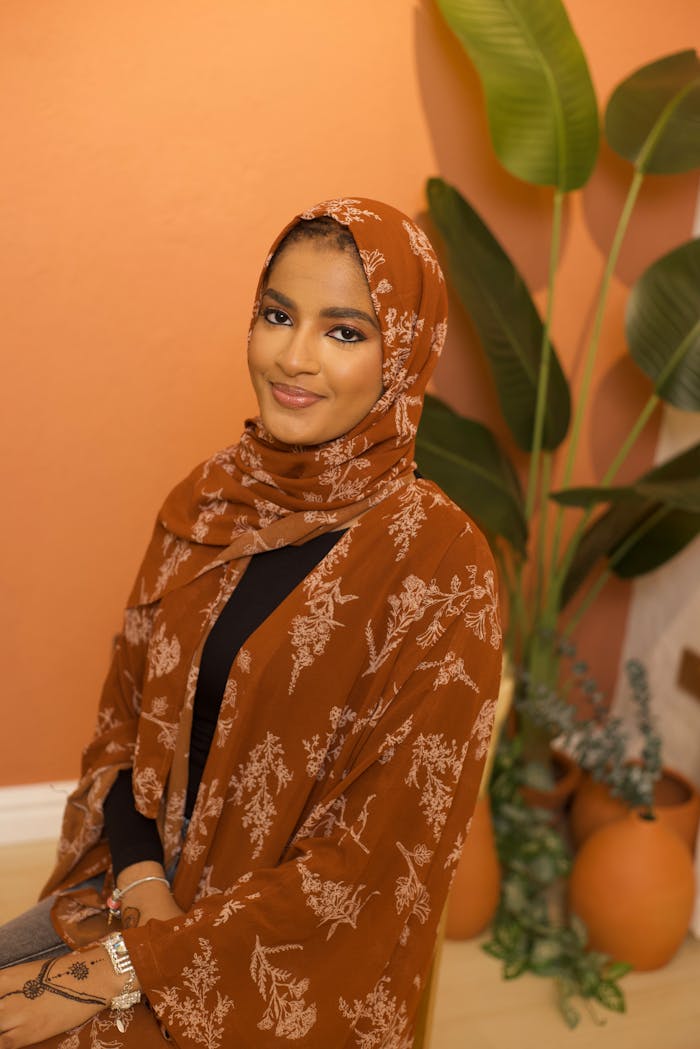Home Young woman in floral hijab with a serene expression in indoor setting.